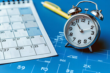 close up of calendar and clock on the blue table background, planning for business meeting or travel planning concept
