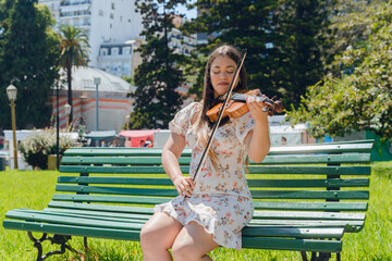 young latin woman violinist busker in park