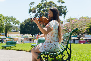 young latin woman violinist busker in park