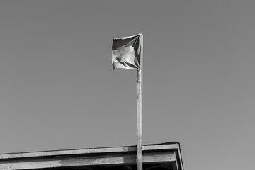 Beach warning flag open on a pole in black and white