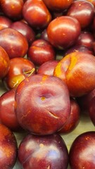 Close up pile of tasty fresh plums sold at the market as a background.