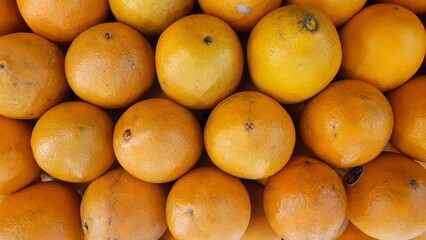 Close up pile of tasty fresh oranges sold at the market as a background.