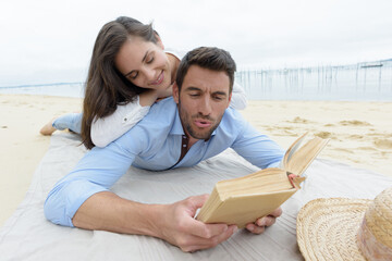 couple on beach reading book