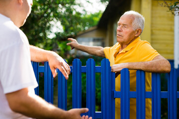 Elderly man discussing with neighbour beside house