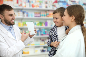 Fototapeta na wymiar Professional pharmacist working with customer in modern drugstore