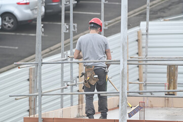 ouvrier montant un échaffaudage sur un chantier de construction - 742766983