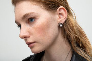Close up portrait of a beautiful elegant woman with freckles with stylish jewelry on a white...