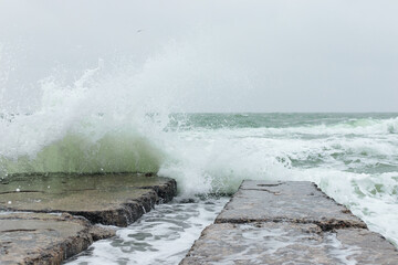 Sea in a storm and a large wave hitting the dock
