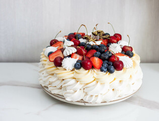 Pavlova cake with whipped cream cheese, chocolate sauce, fresh strawberry, blueberry and raspberry, decorated with meringues on plain background