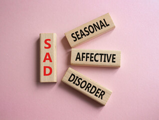 Sad - Seasonal Affective Disorder symbol. Wooden blocks with words Sad. Beautiful pink background. Business and Sad concept. Copy space.