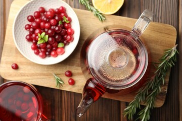 Tasty hot cranberry tea, rosemary and fresh berries on wooden table
