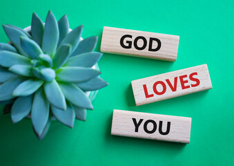 God loves you symbol. Wooden blocks with words God loves you. Beautiful green background with succulent plant. Religion and God loves you concept. Copy space.