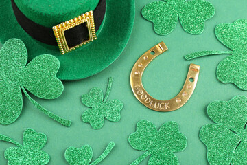 St. Patrick's day. Leprechaun hat, golden horseshoe and decorative clover leaves on green...