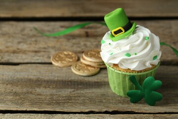 St. Patrick's day party. Tasty cupcake with green leprechaun hat topper on wooden table, closeup....