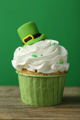 St. Patrick's day party. Tasty cupcake with leprechaun hat topper on wooden table, closeup