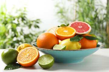 Different cut and whole citrus fruits on white wooden table outdoors