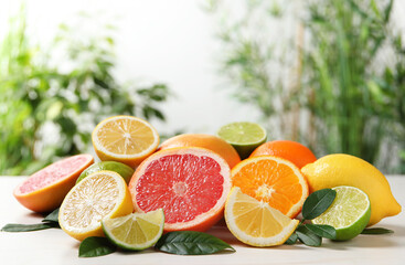 Different cut and whole citrus fruits on white table