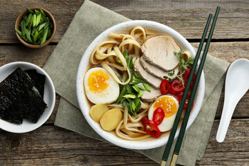 Delicious ramen in bowl served on wooden table, flat lay. Noodle soup