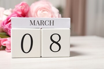 International Women's day - 8th of March. Block calendar and bouquet of beautiful flowers on white wooden table, closeup