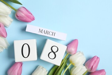 International Women's day - 8th of March. Block calendar and beautiful tulips on light blue background, flat lay. Space for text