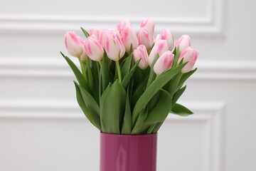 Beautiful bouquet of fresh pink tulips near white wall