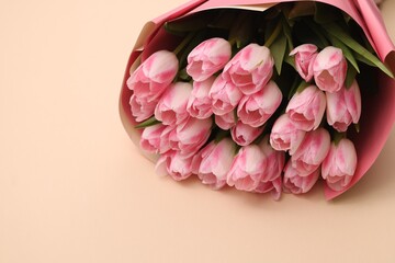 Beautiful bouquet of fresh pink tulips on beige background