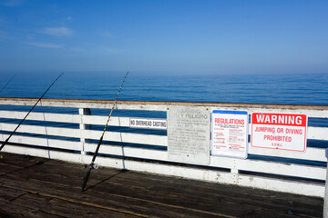 Fishing Rods and warnings about food poisoning and city regulations around beaches, cliffs, walkways and parking areas posted at Crystal Pier, San Diego, California
