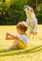 On hot summer day child and family pet dog playing with soap bubbles outdoor