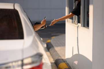 Men scan and pay for food, pick up food from a drive-thru counter and take it to eat at home and at work.