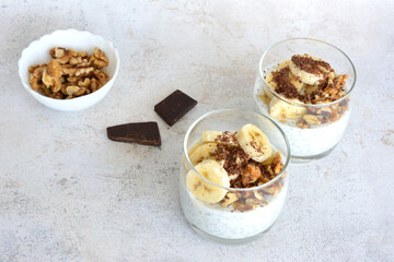 healthy snack with chia pudding, banana, walnut and granola in glass