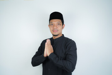 Obraz na płótnie Canvas Happy smiling Asian Muslim man standing with Eid greeting gesture and welcoming Ramadan isolated background