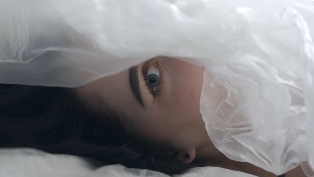Body beauty and fashion advertisement. Close up of woman's face and eyes partially covered by translucent oilcloth.