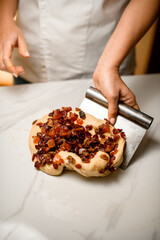 Baker's hands take the dough with raisins with a kitchen spatula