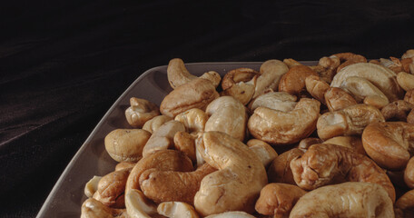 Fototapeta premium Roasted cashew nuts on a plate on a black background