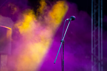 A stage microphone on a smoky purple background. The concert begins.