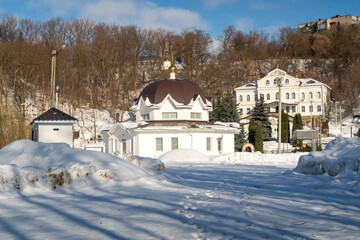 Orthodox church in the forest in winter against the background of a blue sky in sunny weather