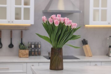 Beautiful bouquet of fresh pink tulips on table in kitchen