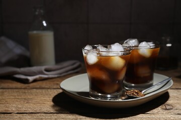 Refreshing iced coffee in glasses, ingredients and spoon on wooden table