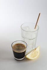 Coffee and ice cubes in different glasses, cut lemon on white background