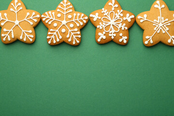 Tasty Christmas cookies with icing on green background, flat lay. Space for text