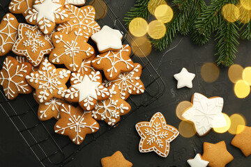 Tasty Christmas cookies with icing and fir tree branches on black table, flat lay