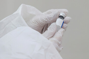 Doctor hands in gloves holds a tube with coronavirus vaccine