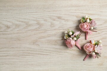 Stylish pink boutonnieres on white wooden table, flat lay. Space for text