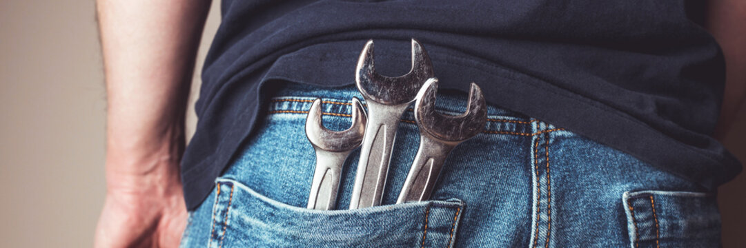 Man with wrenches in back pocket of his jeans banner. Ideal for industrial, mechanical, and DIY projects. Panoramic web header. Wide screen wallpaper.