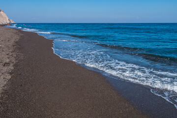 volcanic black sand beach on santorini island in greece and aegean sea