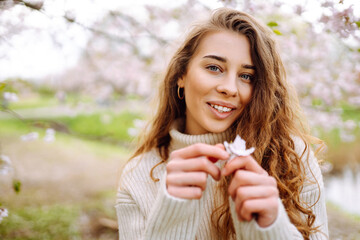 Happy woman enjoying scent in blooming spring garden. The concept of youth, love, fashion, tourism...