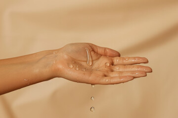 A drops of gel drops on the arm. Palm. Concept for cosmetics. Light beige background, side view. Space for text.