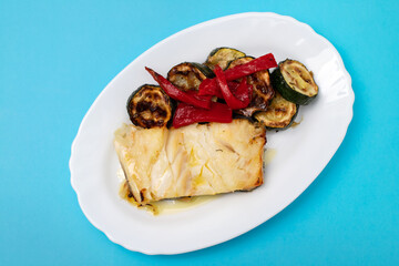 Fish dish - fried cod fish with grilled vegetables in plate