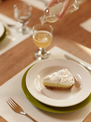 A Happy Dinner Date at Home A beautiful brunette woman is sitting at a trendy dining table, enjoying a romantic homemade meal She is ecstatic and smiling while indulging in a delicious cake and wine