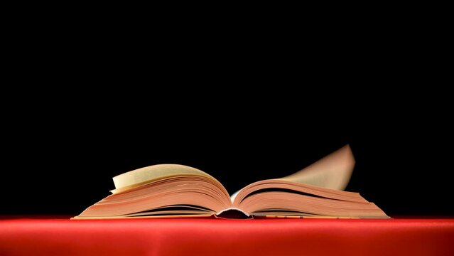 Quickly flipping pages of a thick book on a red black background